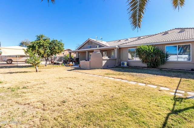 rear view of house featuring a yard, a tiled roof, and stucco siding