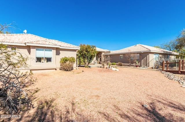 rear view of property featuring a tiled roof and stucco siding