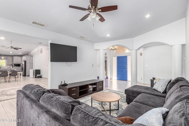 living area featuring ceiling fan, light wood-type flooring, visible vents, and ornate columns