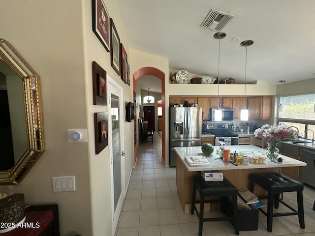 kitchen featuring lofted ceiling, decorative light fixtures, a center island, a kitchen breakfast bar, and stainless steel appliances