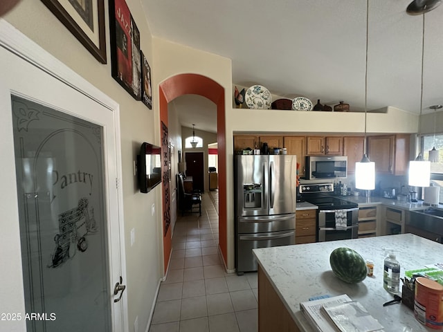 kitchen with light tile patterned flooring, vaulted ceiling, hanging light fixtures, stainless steel appliances, and light stone countertops