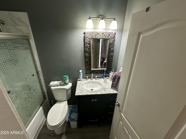 full bathroom featuring vanity, hardwood / wood-style flooring, enclosed tub / shower combo, and toilet