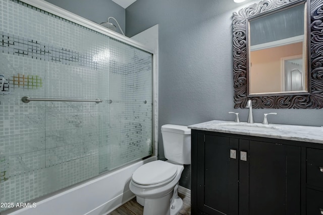 full bathroom with vanity, hardwood / wood-style floors, bath / shower combo with glass door, and toilet