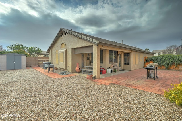 back of house with a storage shed and a patio