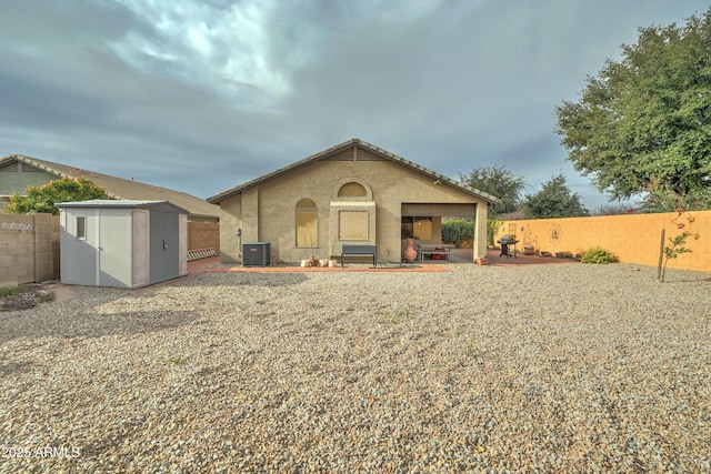 back of property featuring cooling unit, a patio, and a storage unit