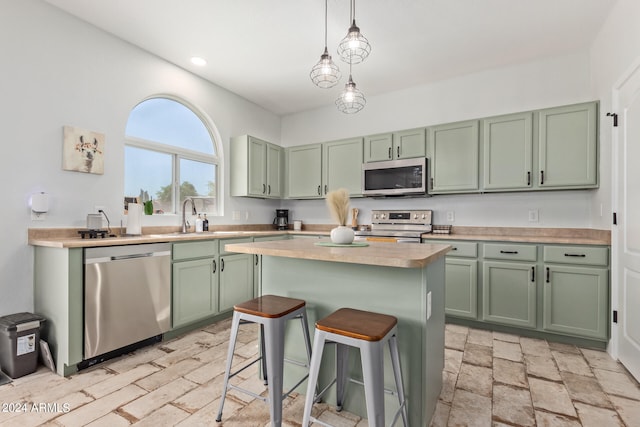 kitchen with a breakfast bar area, decorative light fixtures, green cabinetry, and stainless steel appliances