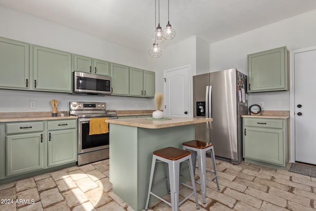 kitchen featuring pendant lighting, green cabinetry, appliances with stainless steel finishes, a center island, and a breakfast bar area