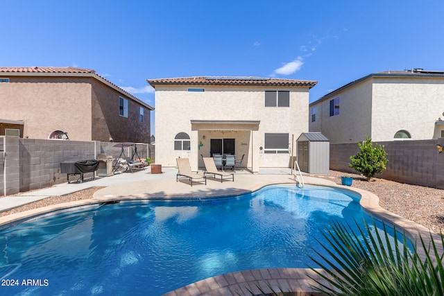 view of pool with a storage shed and a patio area