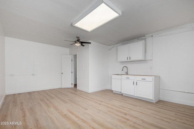 3802 N 48th Dr, Phoenix, AZ 85031 - kitchen featuring ceiling fan, a sink, light wood-style flooring, white cabinetry, and baseboards