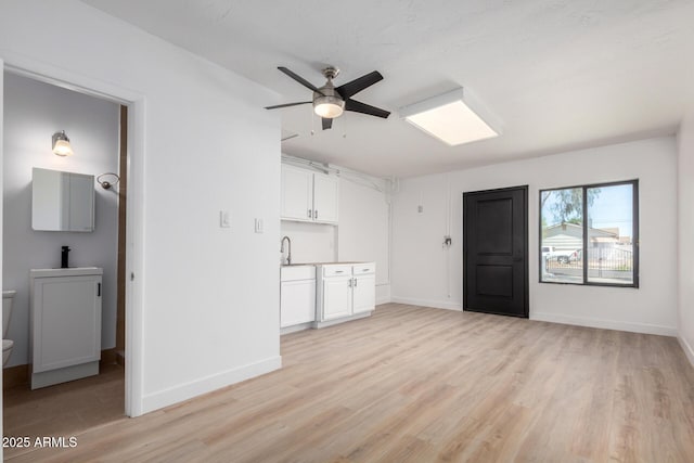 3802 N 48th Dr, Phoenix, AZ 85031 - unfurnished living room with a ceiling fan, baseboards, a sink, and light wood-style flooring