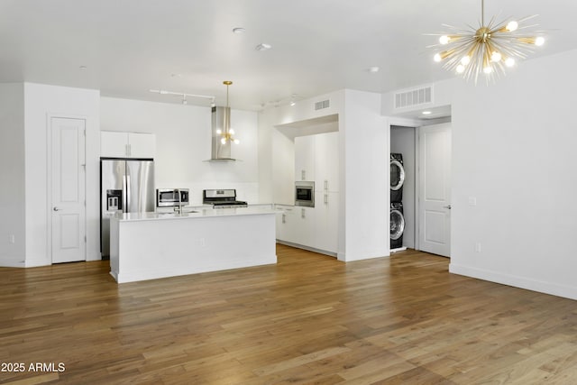 3131 N Central Ave Unit 3009, Phoenix, AZ 85012 - kitchen featuring appliances with stainless steel finishes, stacked washer / drying machine, extractor fan, and white cabinets