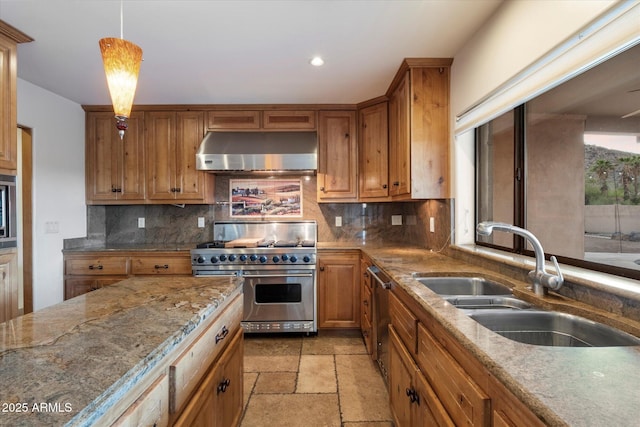 kitchen with under cabinet range hood, stainless steel appliances, a sink, tasteful backsplash, and light stone countertops