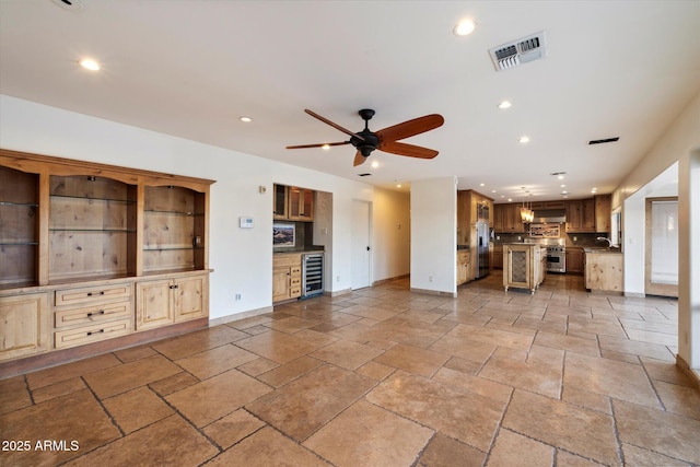 unfurnished living room with beverage cooler, recessed lighting, baseboards, ceiling fan, and stone tile flooring
