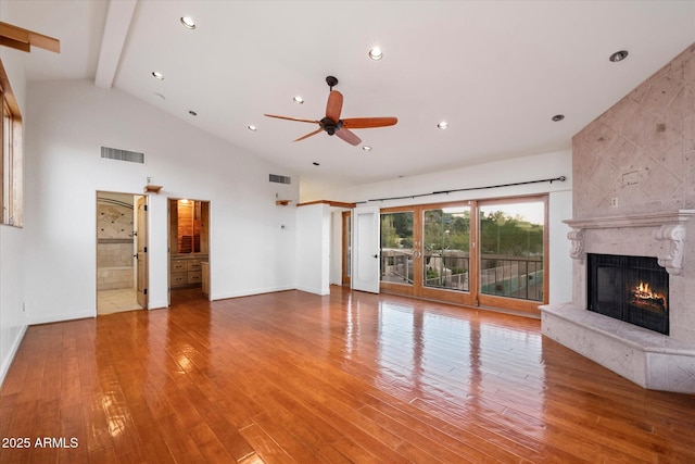 unfurnished living room with a high end fireplace, ceiling fan, wood finished floors, beam ceiling, and baseboards