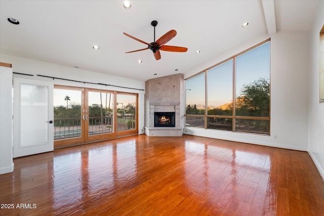 unfurnished living room with a ceiling fan, wood finished floors, a large fireplace, baseboards, and recessed lighting