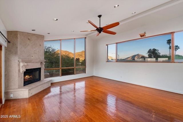 unfurnished living room featuring a fireplace, a ceiling fan, wood-type flooring, recessed lighting, and baseboards