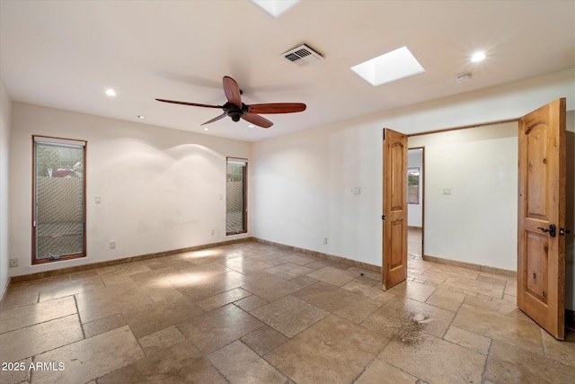 spare room featuring recessed lighting, baseboards, stone tile flooring, a skylight, and ceiling fan