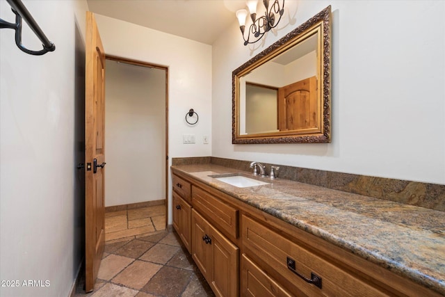 bathroom with stone tile floors, vanity, and baseboards