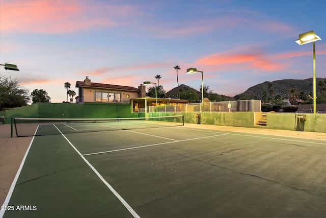 view of tennis court featuring fence and a mountain view