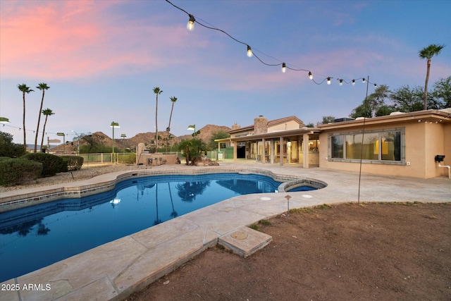view of swimming pool with a patio, fence, and a pool with connected hot tub