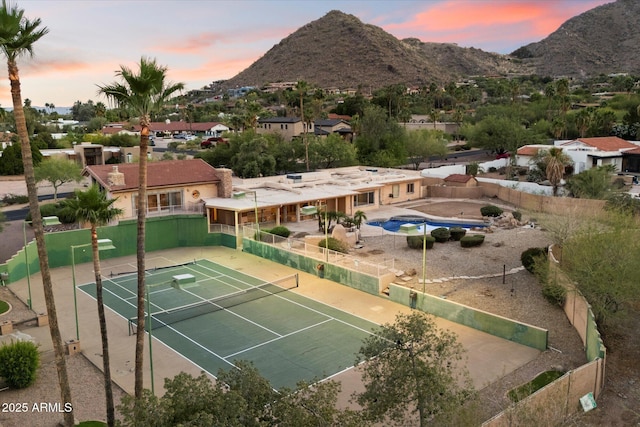 view of tennis court featuring fence and a mountain view