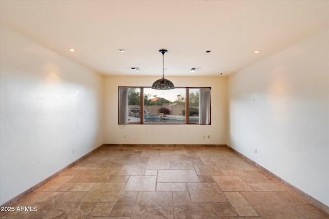 spare room featuring stone tile flooring, recessed lighting, and baseboards