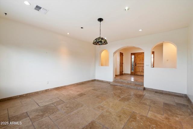 spare room with stone tile floors, baseboards, recessed lighting, and arched walkways
