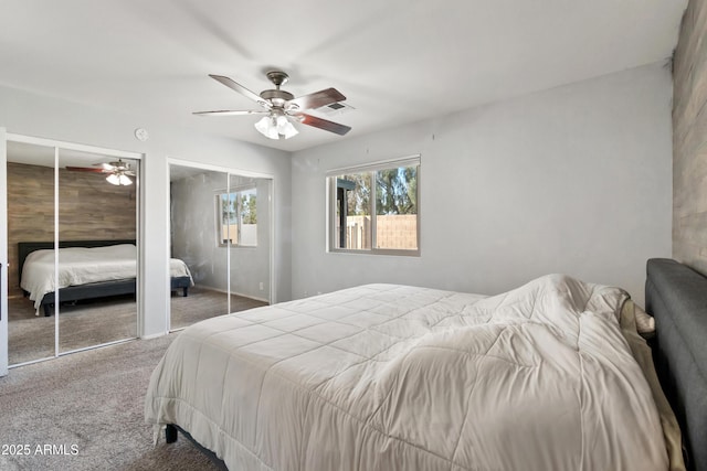 carpeted bedroom with ceiling fan and two closets