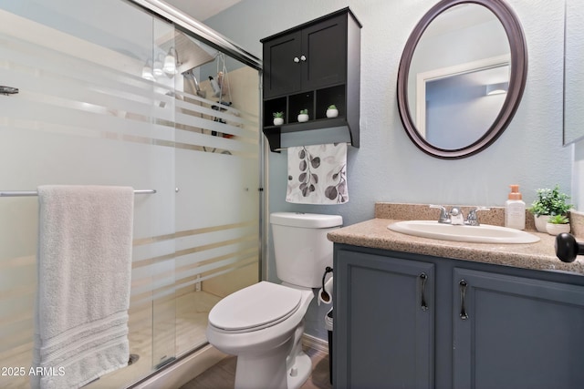 bathroom featuring vanity, toilet, and a shower with door