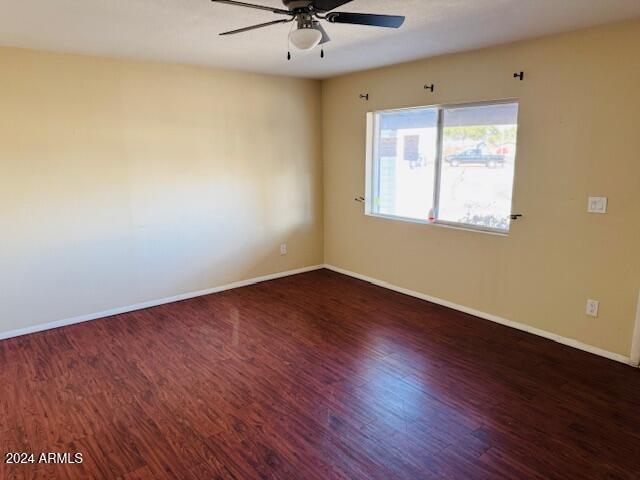 unfurnished room featuring ceiling fan and dark wood-type flooring