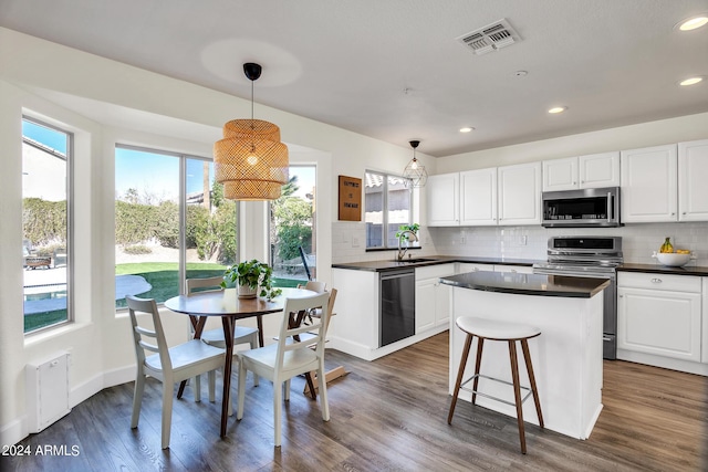 kitchen featuring stainless steel appliances, white cabinets, and decorative light fixtures