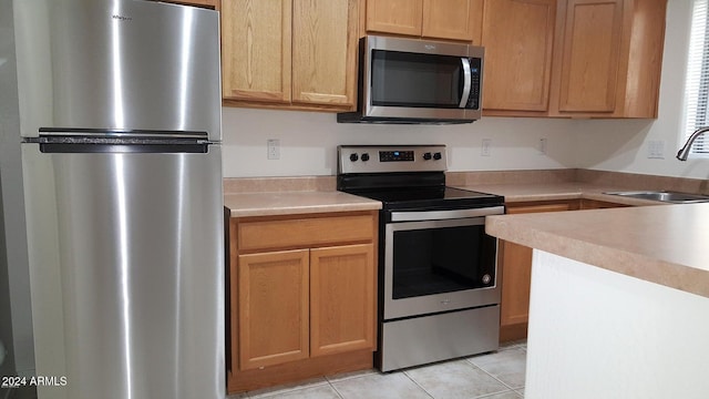 kitchen with sink, light tile patterned floors, and appliances with stainless steel finishes