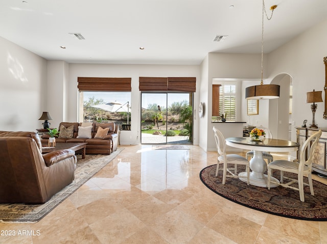 living area with arched walkways, visible vents, baseboards, and recessed lighting