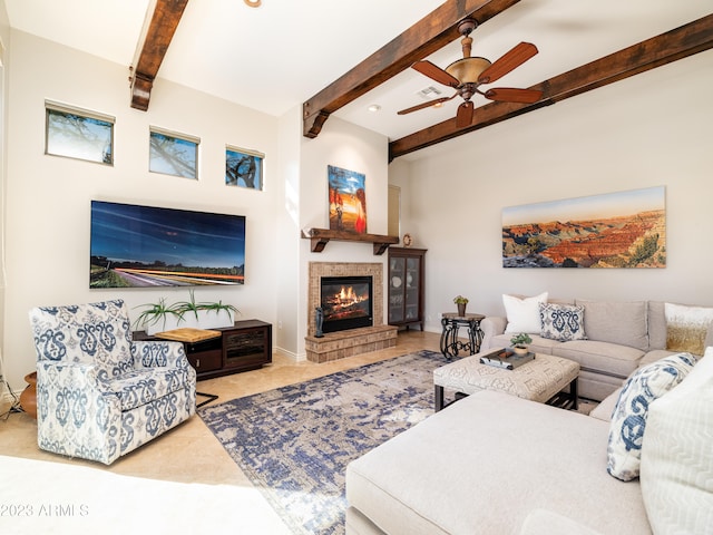 living room featuring ceiling fan, beamed ceiling, and a glass covered fireplace