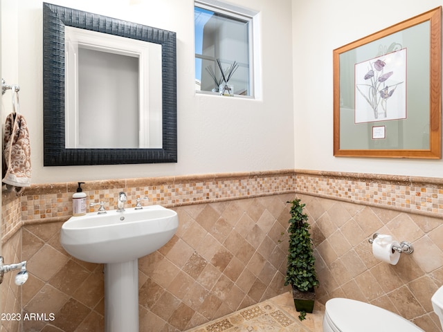 half bath with toilet, tile walls, and wainscoting