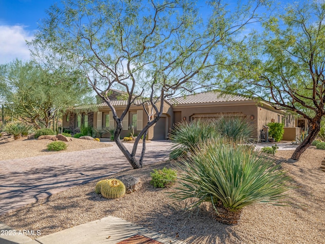 view of front facade featuring a garage, driveway, a tile roof, and stucco siding