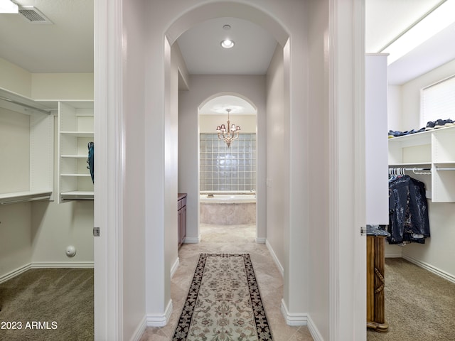 hallway featuring arched walkways, light carpet, visible vents, and baseboards