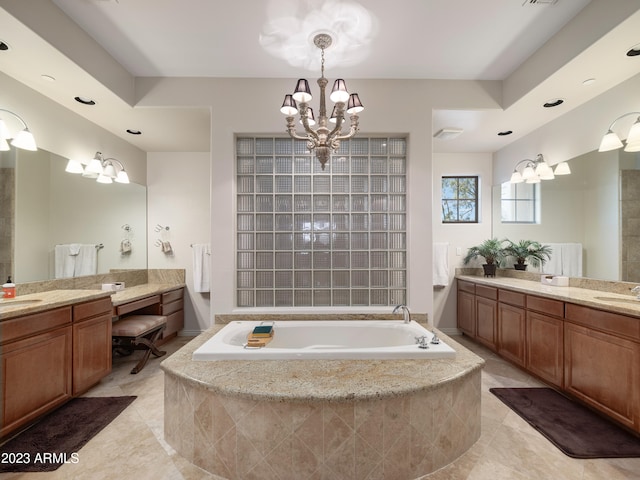 full bath featuring a garden tub, a chandelier, two vanities, and a sink