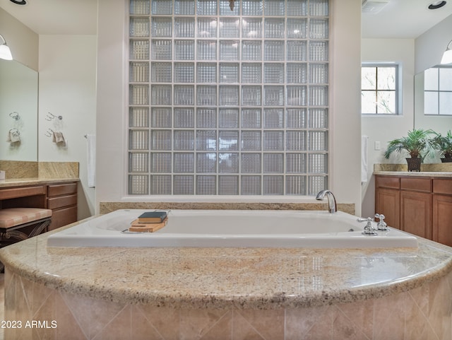 bathroom featuring visible vents, vanity, and a bath