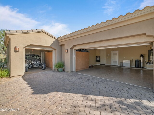 view of front of property featuring decorative driveway, a tiled roof, an attached garage, and stucco siding