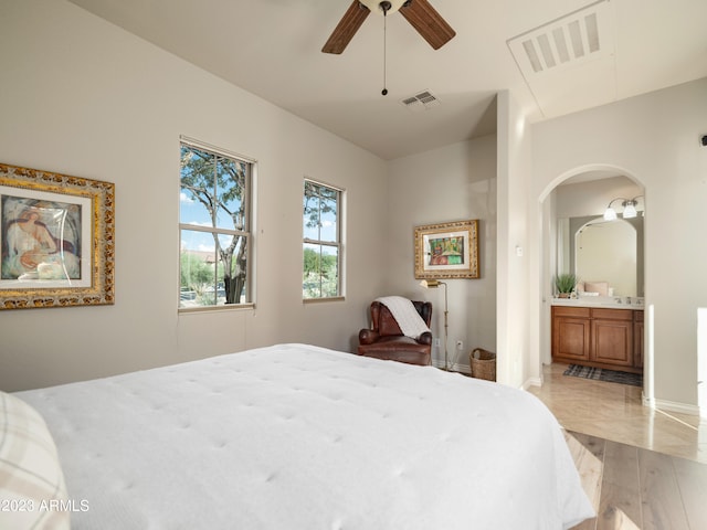 bedroom with arched walkways, visible vents, connected bathroom, and light wood-style flooring