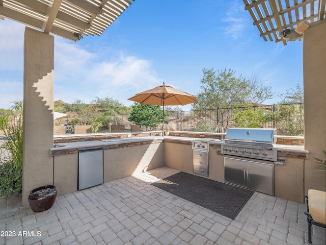 view of patio with exterior kitchen, fence, area for grilling, and a pergola