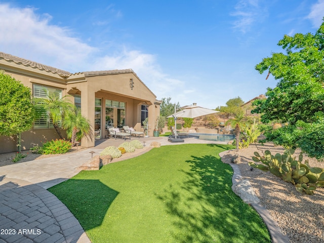 back of property with a tile roof, a lawn, stucco siding, an outdoor pool, and a patio area