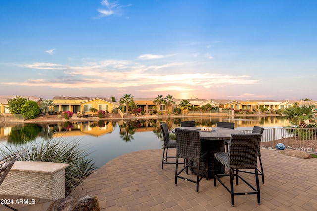 patio terrace at dusk featuring a water view