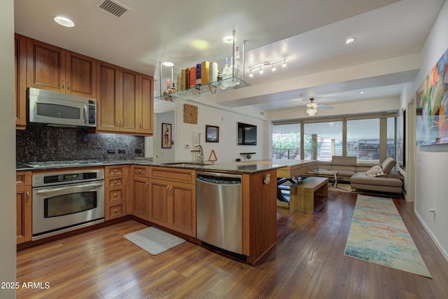 kitchen with decorative backsplash, stainless steel appliances, dark hardwood / wood-style floors, and kitchen peninsula