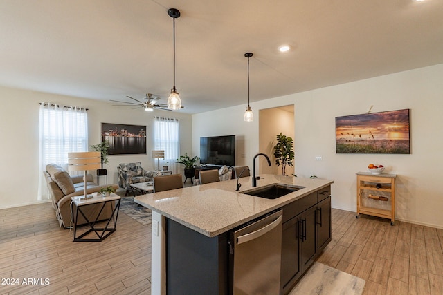 kitchen with a healthy amount of sunlight, stainless steel dishwasher, wood tiled floor, and a sink