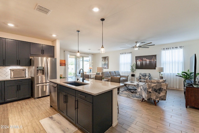 kitchen featuring light wood finished floors, tasteful backsplash, visible vents, appliances with stainless steel finishes, and a sink