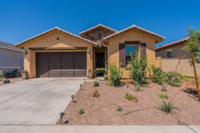 single story home featuring concrete driveway, a tiled roof, an attached garage, and stucco siding