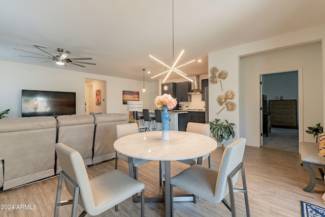 dining room with ceiling fan with notable chandelier, light wood-type flooring, and visible vents