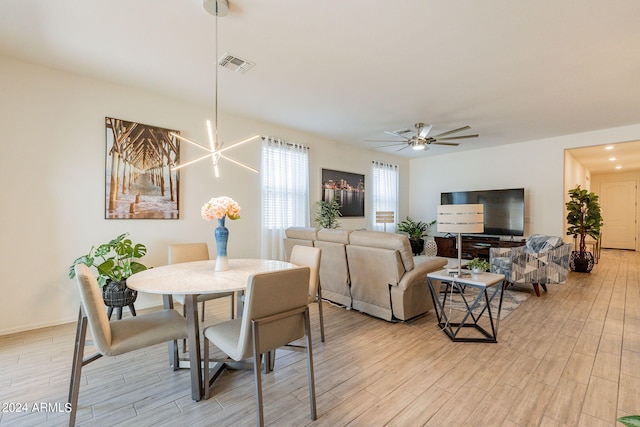 dining room with light wood finished floors, visible vents, and a ceiling fan